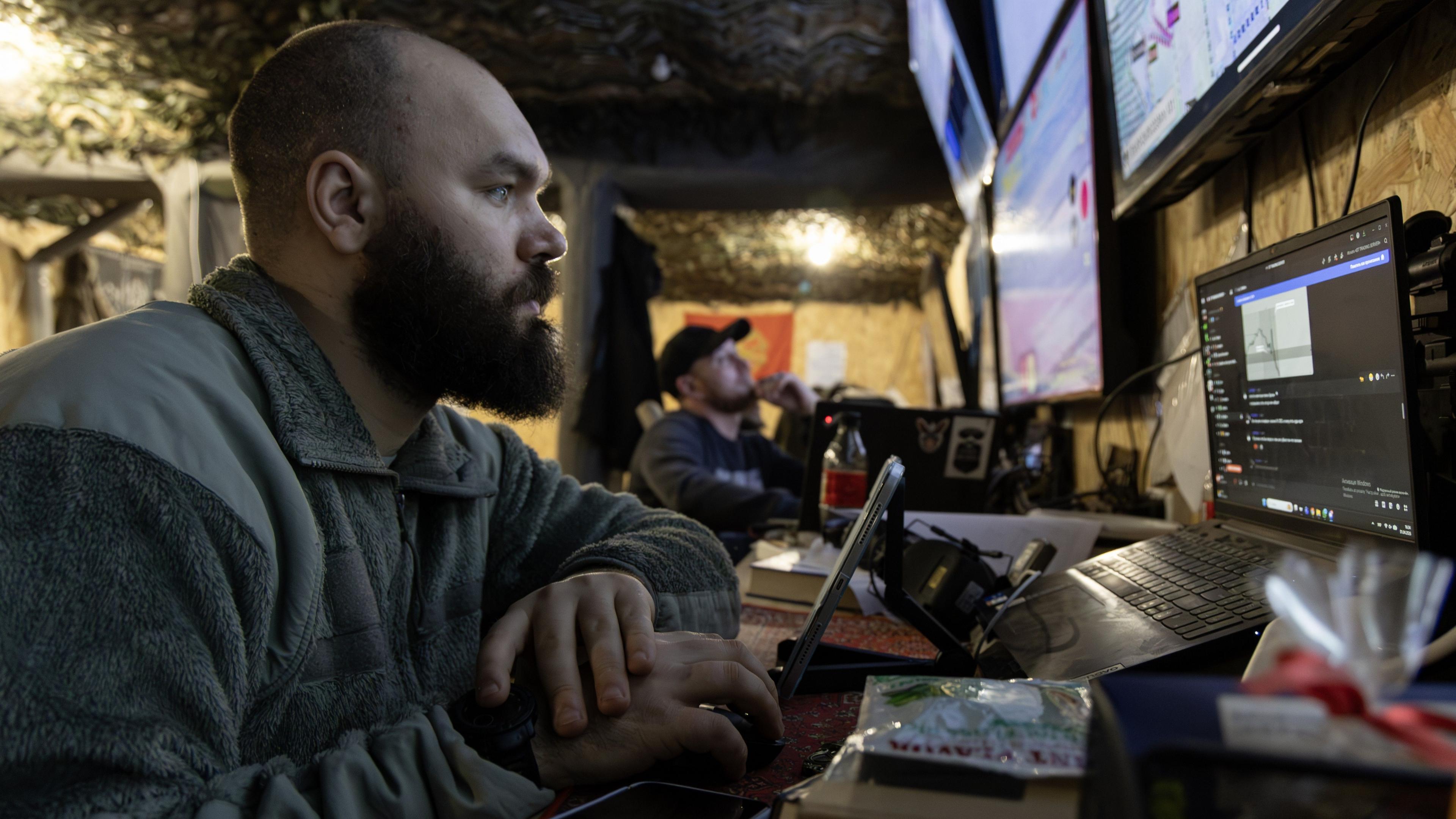 A close up of a Ukrainian soldier surrounded by computer screens