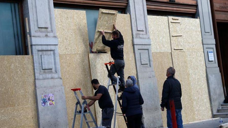 Workers boarding up windows in Lyon ahead of protests